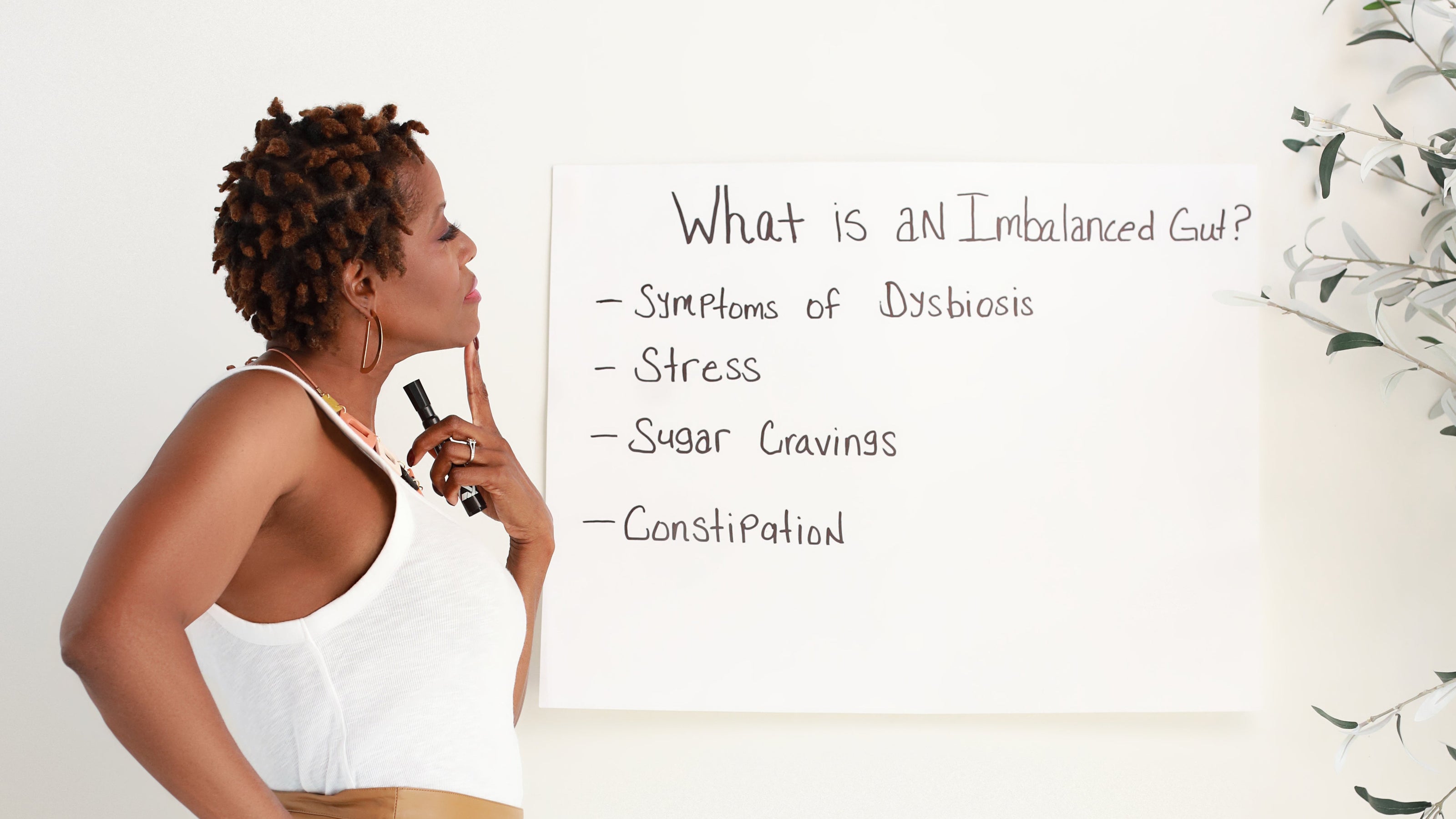 Woman standing next to a whiteboard with notes on an imbalanced gut.