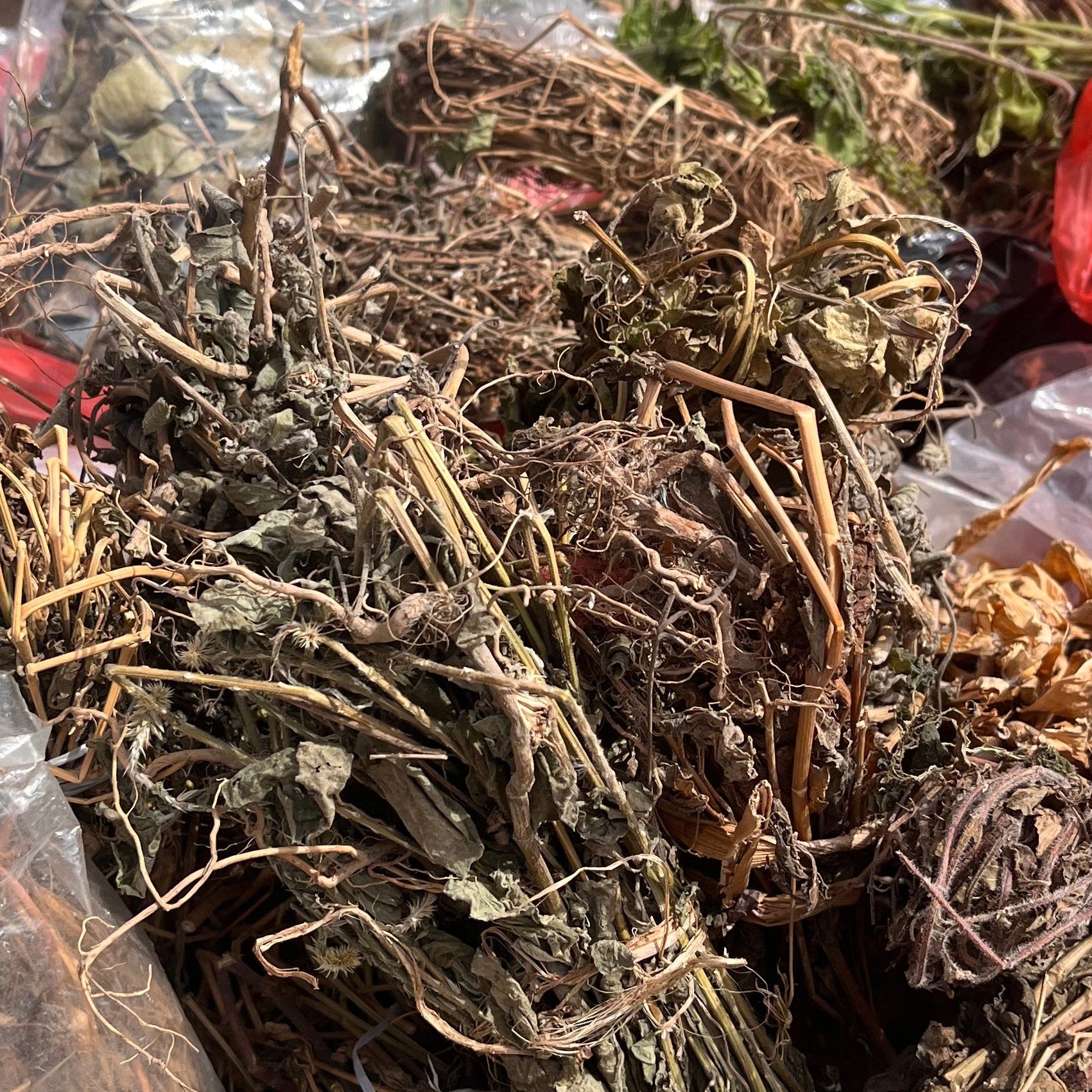 Dry herbs in a plastic bag with bottles in the background
